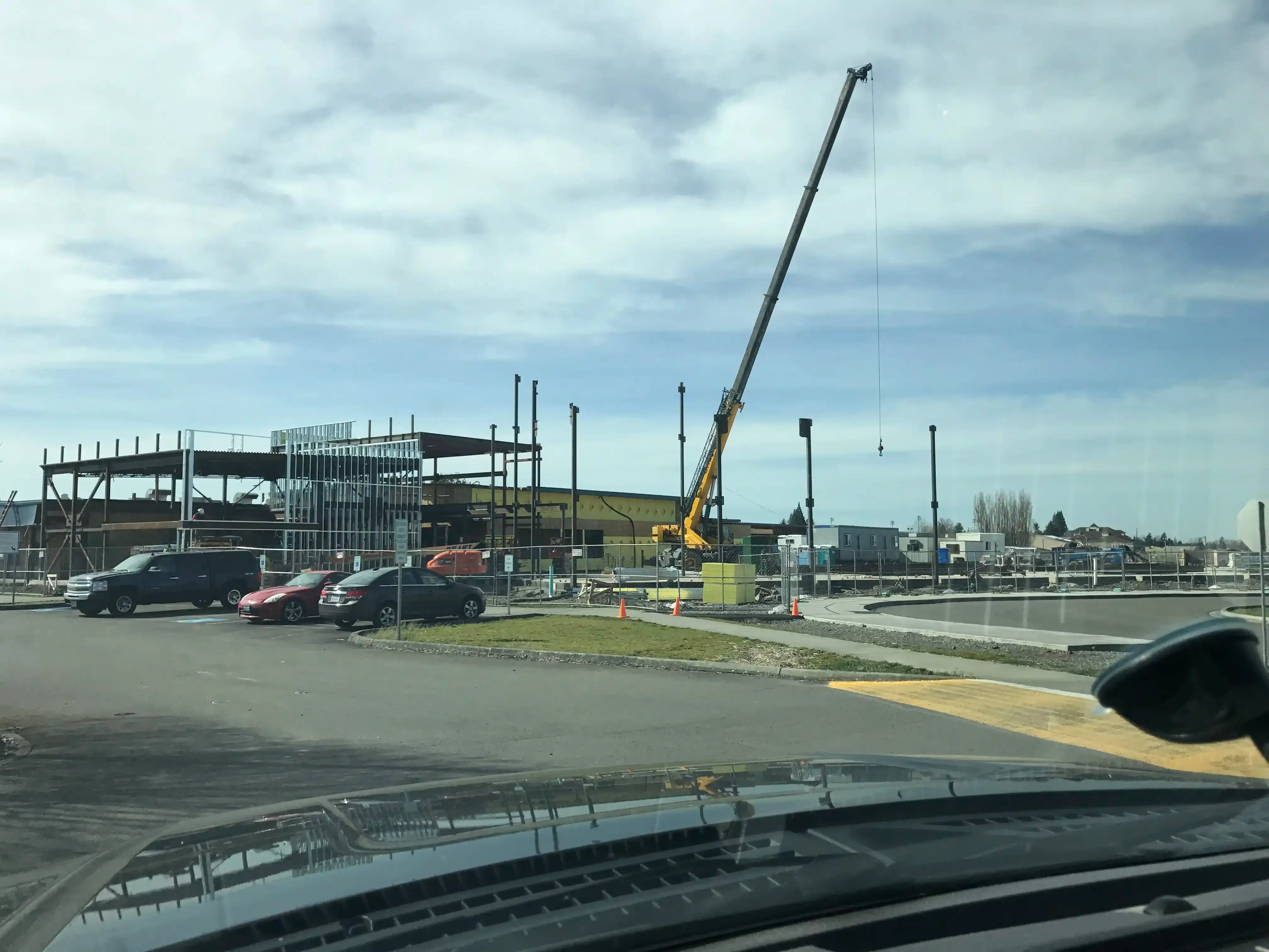 Photo taken from NE of site featuring a large crane in the process of erecting the steel structure of the building.